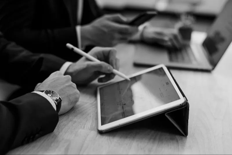 Two people at a table going over notes on a tablet