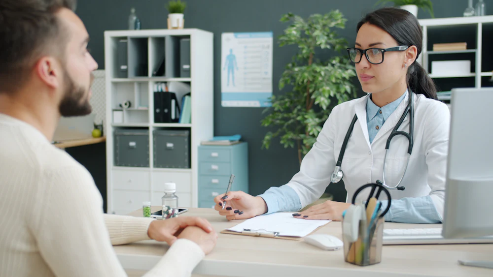 A doctor talking with a patient in a bright office